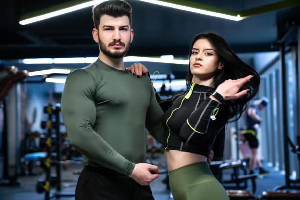 Athletic couple in stylish activewear, showcasing breathable performance gear in a modern gym setting.