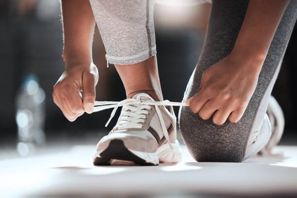 Runner tying shoelaces of lightweight running shoes before a workout, emphasizing preparation for an active lifestyle.
